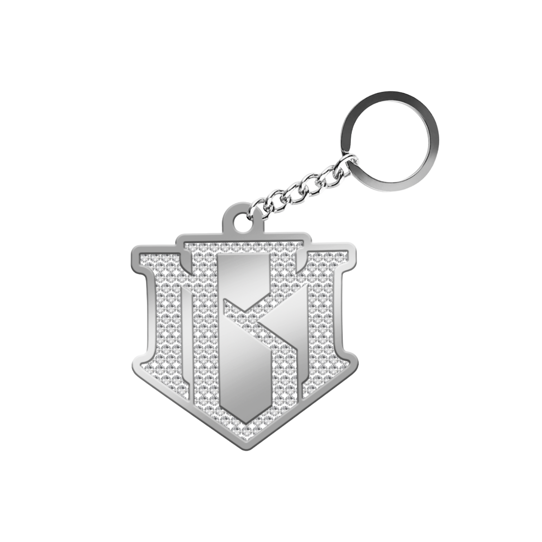 A silver-toned metal keychain featuring a shield-shaped pendant with a textured, rhinestone-embellished design and a polished central letter 'K', attached to a short chain and split ring on a plain white background.